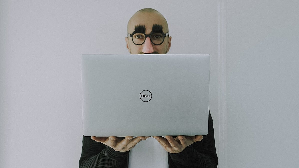 Zu sehen ist ein Mitarbeiter, der privates Surfen im internet mit Hilfe einer Verkleidung darstellt.