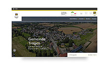 Luftaufnahme der Gemeinde Trogen mit ländlicher Umgebung. Im Vordergrund sind Häuser und Felder zu sehen. Der Schriftzug „Gemeinde Trogen – gemeinsam familiär leben“ ist prominent platziert.