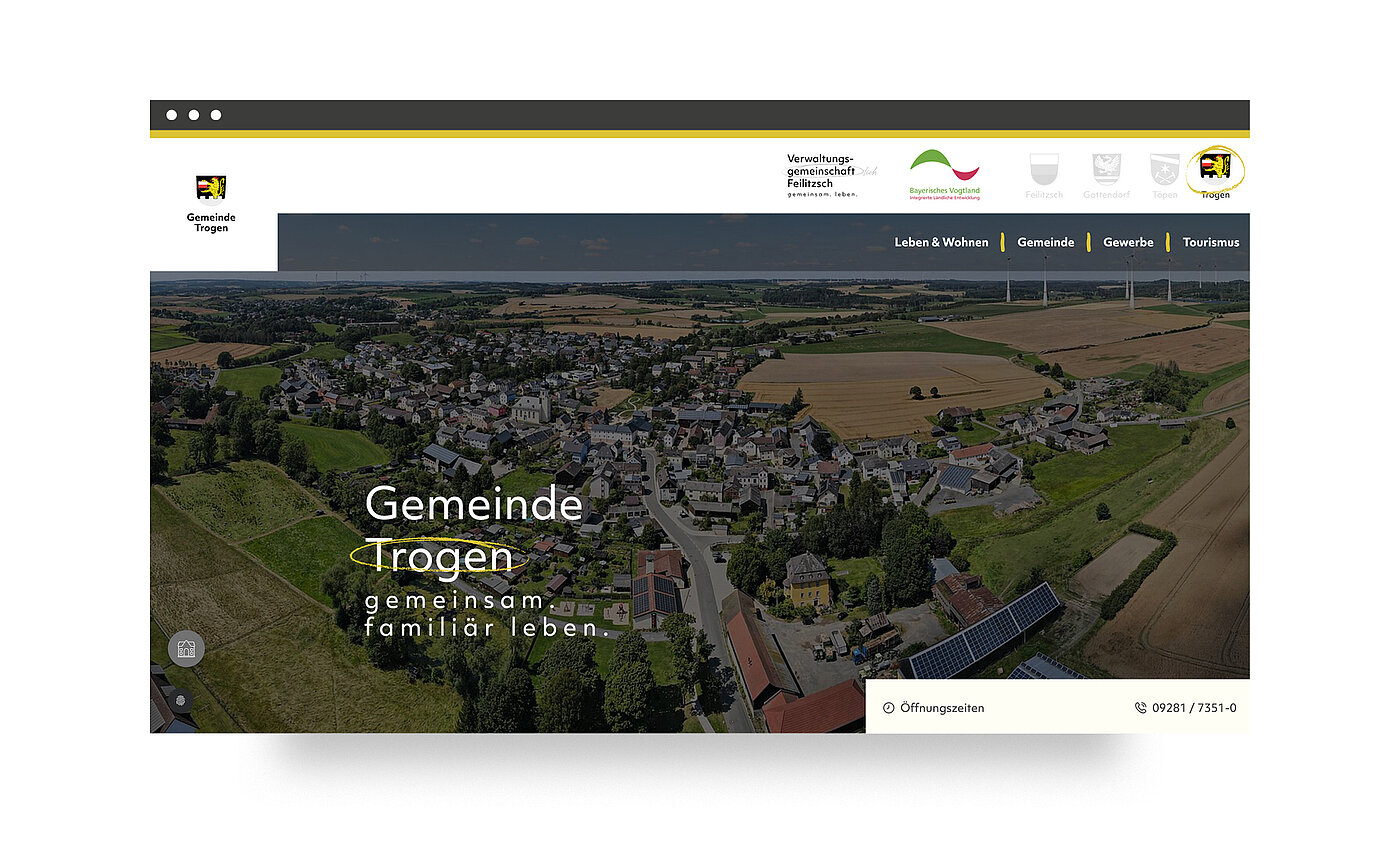 Luftaufnahme der Gemeinde Trogen mit ländlicher Umgebung. Im Vordergrund sind Häuser und Felder zu sehen. Der Schriftzug „Gemeinde Trogen – gemeinsam familiär leben“ ist prominent platziert.