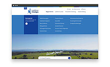 Webseite des Landkreises Ostalgau mit einem blauen Menü oben. Das Hauptthema ist das Serviceportal mit verschiedenen Kategorien wie Familie, Gesundheit und Bildung. Im Hintergrund ist eine Landschaft mit sanften Hügeln und einem klaren Himmel zu sehen.